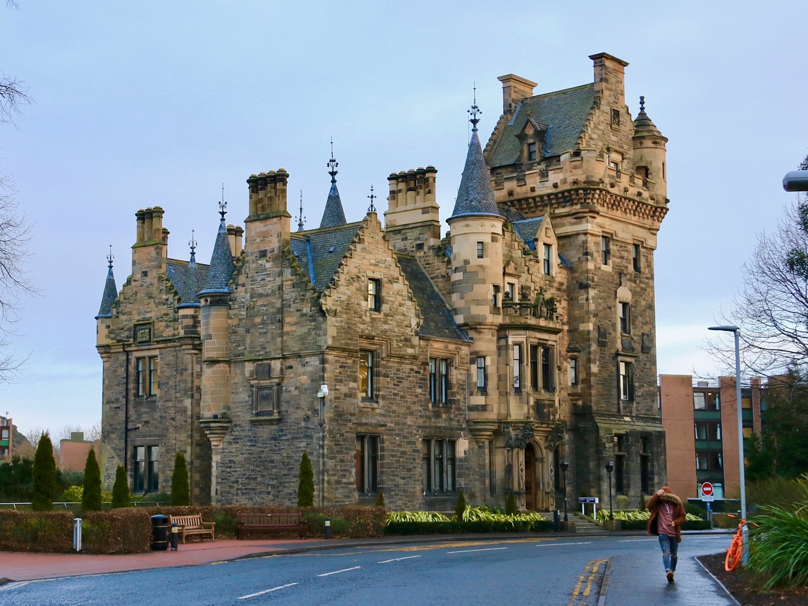 a person walking down a street in front of a large building